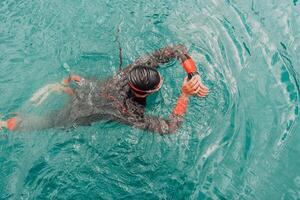 A triathlete in a professional swimming suit trains on the river while preparing for Olympic swimming photo