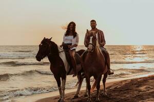 A loving couple in summer clothes riding a horse on a sandy beach at sunset. Sea and sunset in the background. Selective focus photo