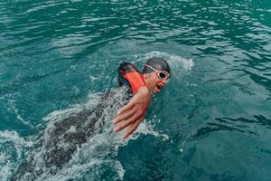 A triathlete in a professional swimming suit trains on the river while preparing for Olympic swimming photo