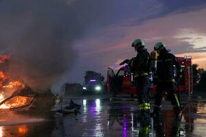 bomberos lucha el fuego fuego a controlar fuego no a extensión afuera. bombero industrial y público la seguridad concepto. tráfico o coche accidente rescate y ayuda acción. foto