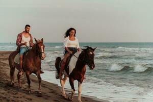 A loving couple in summer clothes riding a horse on a sandy beach at sunset. Sea and sunset in the background. Selective focus photo