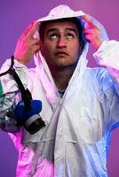 Coronavirus covid-19 pandemic. Doctor scientist wearing protective biological suit and mask due to global healthcare epidemic warning and danger background in blue and pink neon lights background. photo