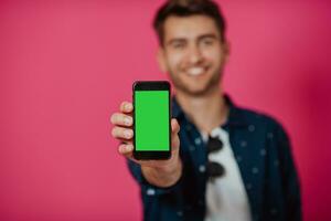 retrato de un contento hombre utilizando teléfono inteligente aislado terminado rosado antecedentes. foto