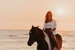 mujer vestida de verano disfruta montando a caballo en una hermosa playa de arena al atardecer. enfoque selectivo foto