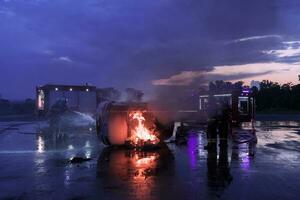 Firefighters using water fire extinguisher to fighting with the fire flame in car accident. Firefighter industrial and public safety concept rescue in night. photo