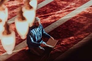 A Muslim reads the holy Islamic book Quraqn in a modern grand mosque during the Muslim holy month of Ranazan photo