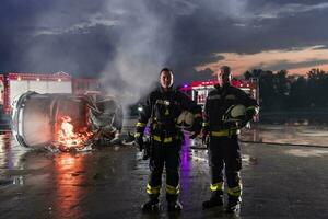 Brave Firefighters Team Walking to the Camera. In Background Paramedics and Firemen Rescue Team Fight Fire in Car Accident, Insurance and Save Peoples Lives concept. photo