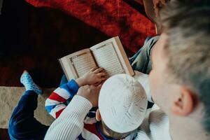 Muslim prayer father and son in mosque praying and reading holly book Quran together islamic education concept photo