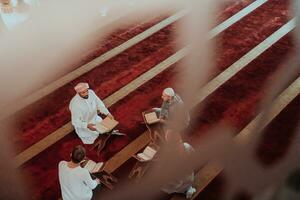 un grupo de musulmanes leyendo el santo libro de el Corán en un moderno mezquita durante el musulmán fiesta de Ramadán foto