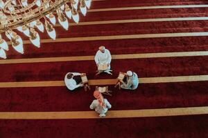 A group of Muslims reading the holy book of the Quran in a modern mosque during the Muslim holiday of Ramadan photo