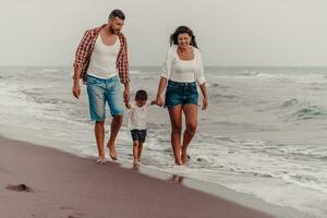 The family enjoys their vacation as they walk the sandy beach with their son. Selective focus photo