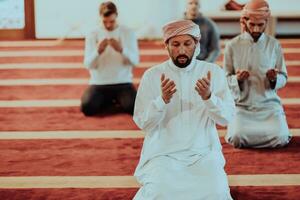 un grupo de musulmanes en un moderno mezquita Orando el musulmán oración namaz, durante el santo mes de Ramadán foto