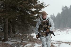 Winter war in the Arctic mountains. Operation in cold conditions.Soldier in winter camouflaged uniform in Modern warfare army on a snow day on forest battlefield with a rifle. Selective focus photo