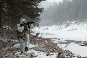 guerra de invierno en las montañas árticas. operación en condiciones frías. soldado en uniforme camuflado de invierno en el ejército de guerra moderno en un día de nieve en el campo de batalla del bosque con un rifle. enfoque selectivo foto