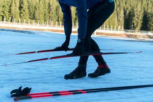 hermoso masculino atleta con cruzar país esquís preparando equipo para formación en un Nevado bosque. comprobación reloj inteligente. sano invierno estilo de vida. foto