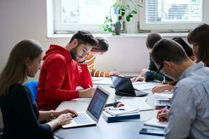 grupo de estudiantes trabajando juntos en un proyecto escolar en una tableta en una universidad moderna foto