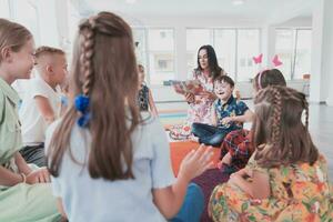 Reading time in an elementary school or kindergarten, a teacher reads a book to children in an elementary school or kindergarten. The concept of pre-school education. Selective focus photo