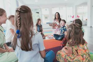 Reading time in an elementary school or kindergarten, a teacher reads a book to children in an elementary school or kindergarten. The concept of pre-school education. Selective focus photo