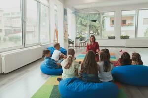 Reading time in an elementary school or kindergarten, a teacher reads a book to children in an elementary school or kindergarten. The concept of pre-school education. Selective focus photo