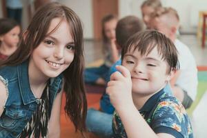 un niña y un chico con abajo síndrome en cada otros brazos gastar hora juntos en un preescolar institución foto