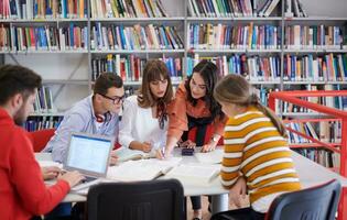 grupo de estudiantes trabajando juntos en un proyecto escolar en una tableta en una universidad moderna foto