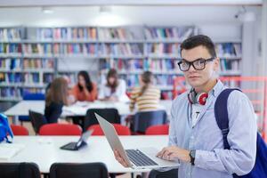 the student uses a notebook, latop and a school library photo