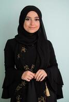 beautiful muslim woman in fashinable dress with hijab isolated on modern cyan background representing concept of modern islam and ramadan kareem photo