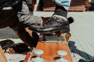 An old man hand polishing and painting a black shoe at street photo