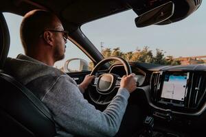 un hombre con un Gafas de sol conducción un coche a puesta de sol. el concepto de coche viaje foto