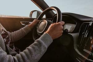 cerca arriba hombre mano conducción un coche a puesta de sol. el concepto de coche viaje foto