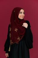 beautiful muslim woman in fashinable dress with hijab isolated on modern red background representing concept of modern islam and ramadan kareem photo