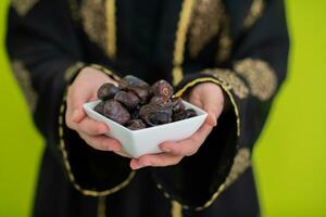 moderno musulmán mujer participación un plato lleno de dulce fechas en iftar hora en Ramadán kareem islámico sano comida concepto OVNI verde antecedentes foto