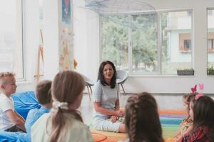 Reading time in an elementary school or kindergarten, a teacher reads a book to children in an elementary school or kindergarten. The concept of pre-school education. Selective focus photo