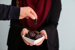 modern muslim woman holding a plate full of sweet dates on iftar time in ramadan kareem islamic healthy food concept photo