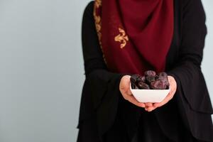 modern muslim woman holding a plate full of sweet dates on iftar time in ramadan kareem islamic healthy food concept photo