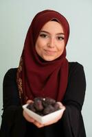 modern muslim woman holding a plate full of sweet dates on iftar time in ramadan kareem islamic healthy food concept photo