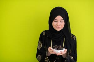 modern muslim woman holding a plate full of sweet dates on iftar time in ramadan kareem islamic healthy food concept ufo green background photo