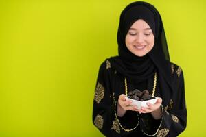 modern muslim woman holding a plate full of sweet dates on iftar time in ramadan kareem islamic healthy food concept ufo green background photo
