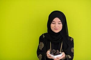 modern muslim woman holding a plate full of sweet dates on iftar time in ramadan kareem islamic healthy food concept ufo green background photo