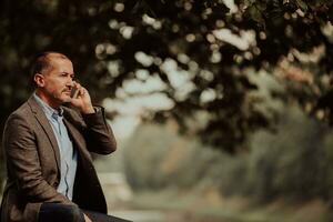 Modern senior businessman in suit uses smartphone in urban environment. photo