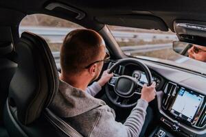 un hombre con un Gafas de sol conducción un coche a puesta de sol. el concepto de coche viaje foto