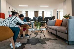 Group of casual multiethnic business people taking break from the work doing different things while enjoying free time in relaxation area at modern open plan startup office photo