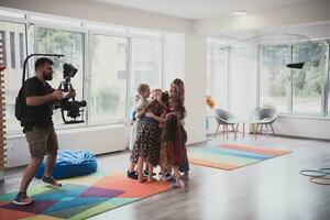 a videographer with a professional camera records children's socializing in a preschool institution photo