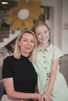 A cute little girl kisses and hugs her mother in preschool photo