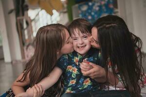 A girl and a woman hug a child with down syndrome in a modern preschool institution photo