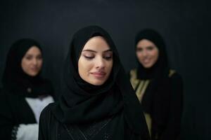 grupo retrato de hermosa musulmán mujer en un de moda vestir con hijab aislado en negro antecedentes foto