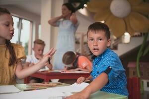 linda niña y chico sentar y dibujar juntos en preescolar institución foto