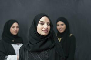 Group portrait of beautiful Muslim women in a fashionable dress with hijab isolated on black background photo