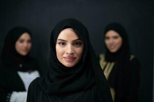 Group portrait of beautiful Muslim women in a fashionable dress with hijab isolated on black background photo