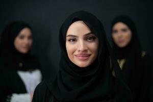 grupo retrato de hermosa musulmán mujer en un de moda vestir con hijab aislado en negro antecedentes foto